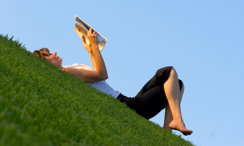 Woman reading on a grass slope