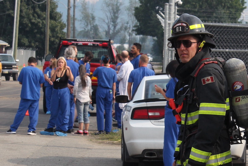 Employees at an Okanagan cannabis facility stand across the road after being evacuated.