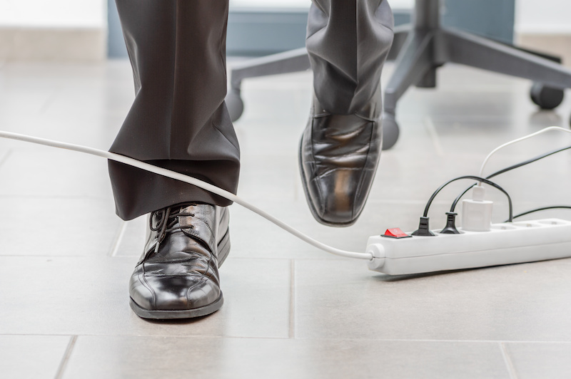 A business man trips over a cord in a workplace accident